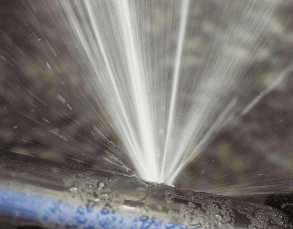 Close-up of water spurting from a leaky irrigation pipe